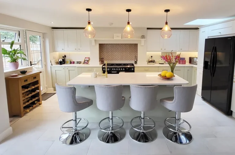 Kitchen with white units and a breafast bar island and four stools.