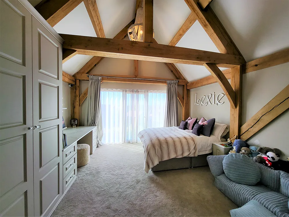 Fitted bedroom units in a room with oak timbers and carpet.