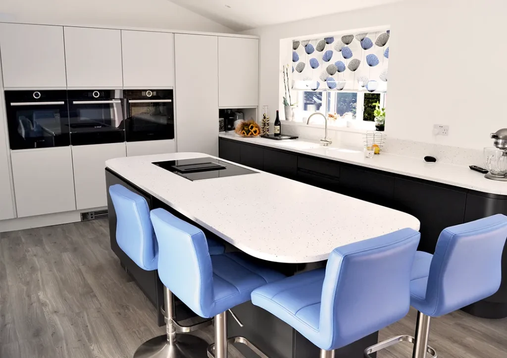 Handleless kitchen with triple oven and breakfast bar with induction hob.
