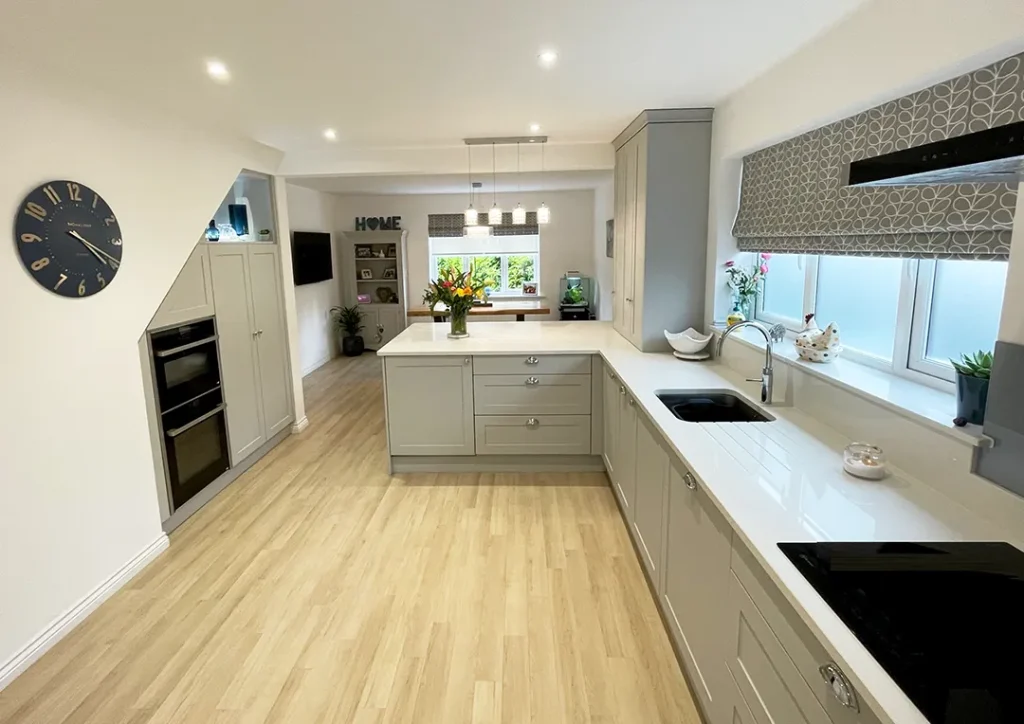 Shaker style kitchen units with chrome handles and white gloss worktop.