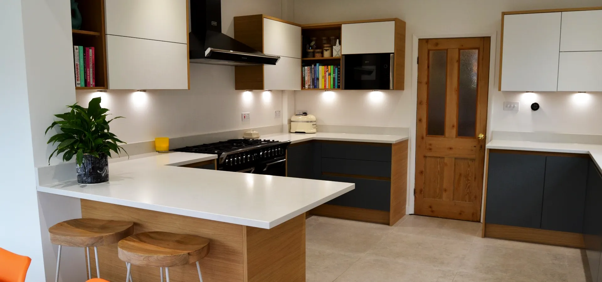 Modern kitchen with white worktops and charcoal drey units with wooden surrounds.