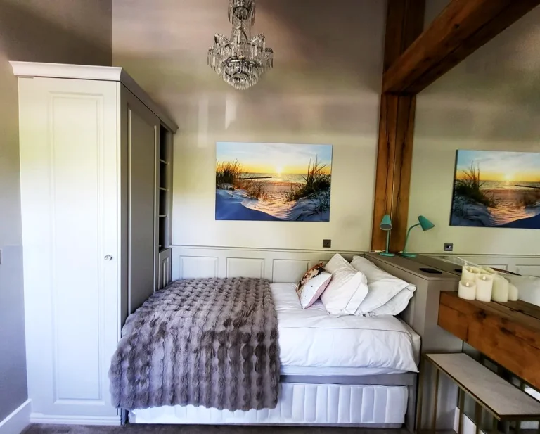 Bespoke bedroom wardrobes fitted around bed with oak framed mirror on wall.