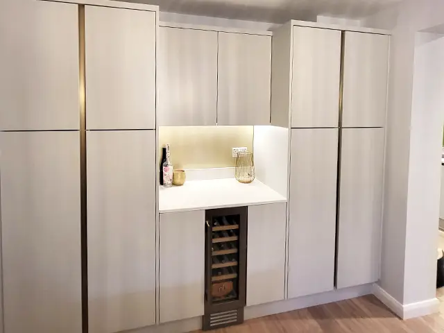 A drinks making nook with a slimline wine cooler surrounded by handleless kitchen cabinetry.