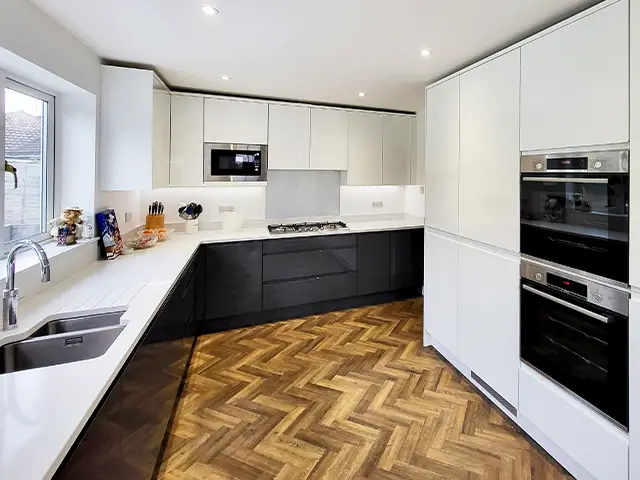 A large kitchen with glossy white handleless doors and a white quartz worktop.