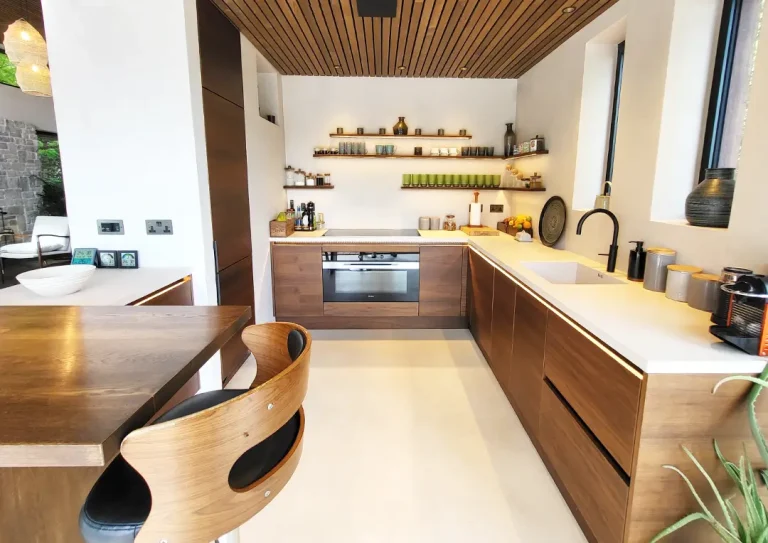 Minimalist Scandinavian style kitchen with clean, unbroken lines created by wooden handleless doors and a white quartz worktop.