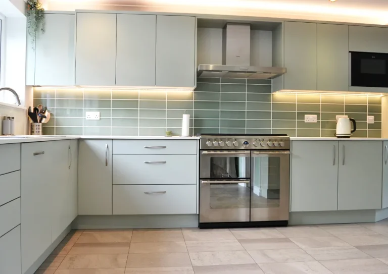 A newly designed and installed Scandinavian-style kitchen with meadow green cabinets, a lightly coloured quartz worktop and stainless steel gas range cooker.