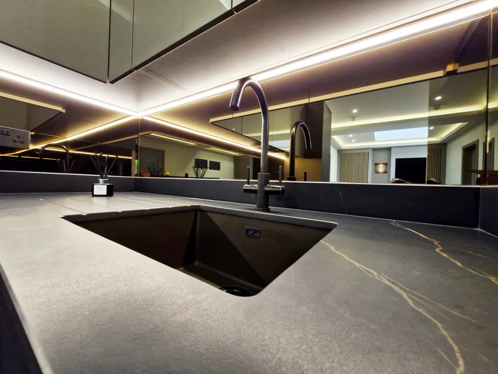 Dark worktop with bronze veins running through the matt black surface and a granite sink with blackened bronze tap.