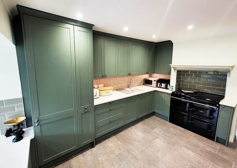 Plain Shaker Split Level Kitchen with green tiles and Aga cooker.