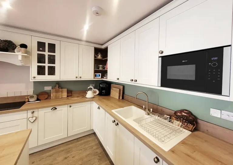 Kitchen with plain shaker doors with brass handles and a laminate worktop in a woodgrain effect to match carcasses.