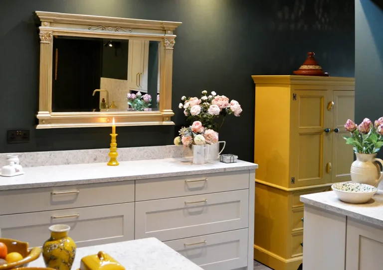 Traditional painted shaker style kitchen units painted in mussel with a patterned quartz worktop in a kitchen painted with dark green walls.
