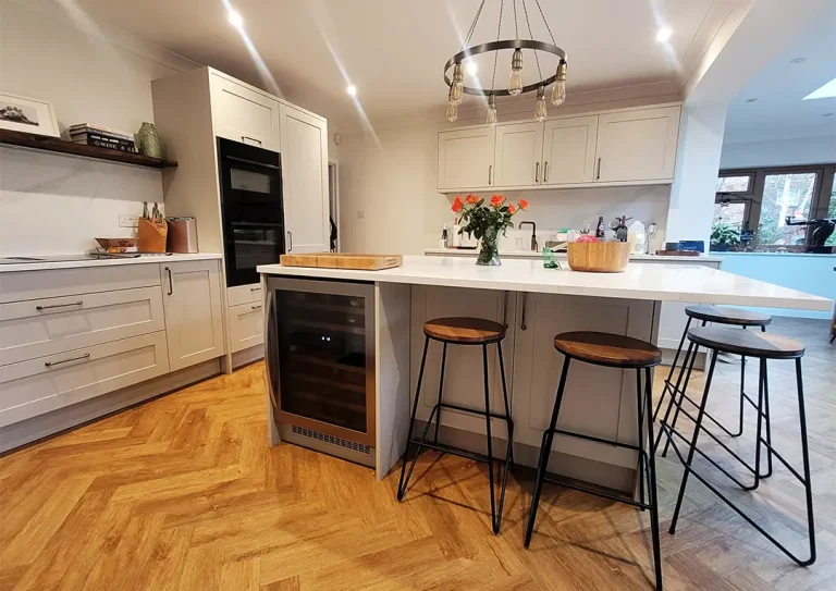 Kitchen with timber doors in painted taupe, kitchen island, wine cooler, stools and built in oven.