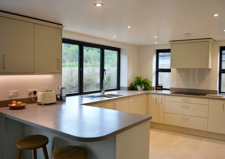 Flat slab kitchen with Corian worktops, hob, under cabinet LED lighting and breakfast bar