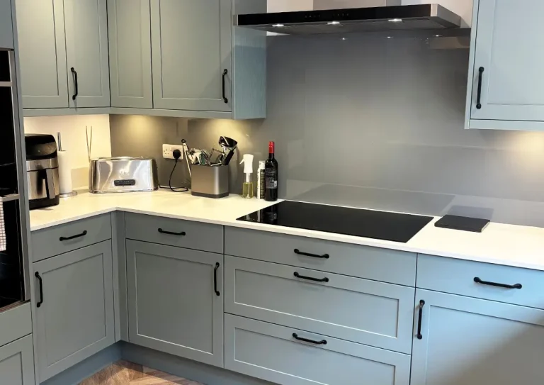 Detail of an induction hob, toaster and utensils in a classic shaker style kitchen in Fjord with black handles.